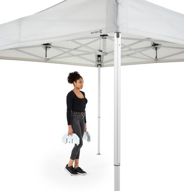 The woman carries the 20 kg base plate to the folding gazebo.